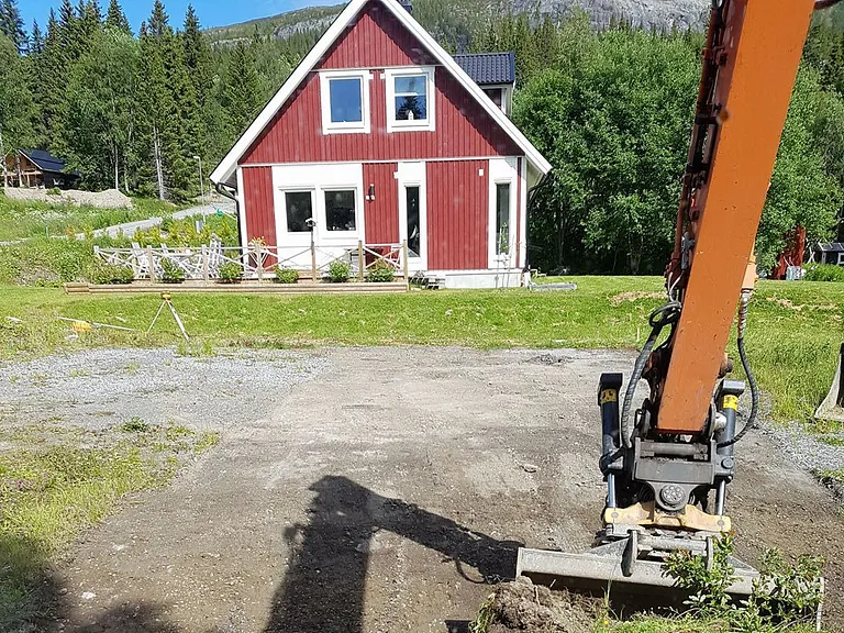 Markplanering. Bilden föreställer en grävskopa som plattar ut en tomt för en bättre markplanering.